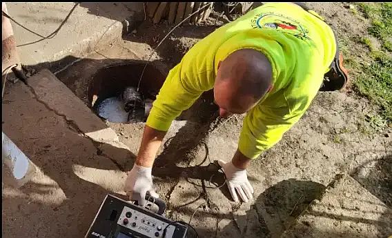 Egy szakember kamerát használ a csatorna diagnosztikájához egy nyitott aknában.