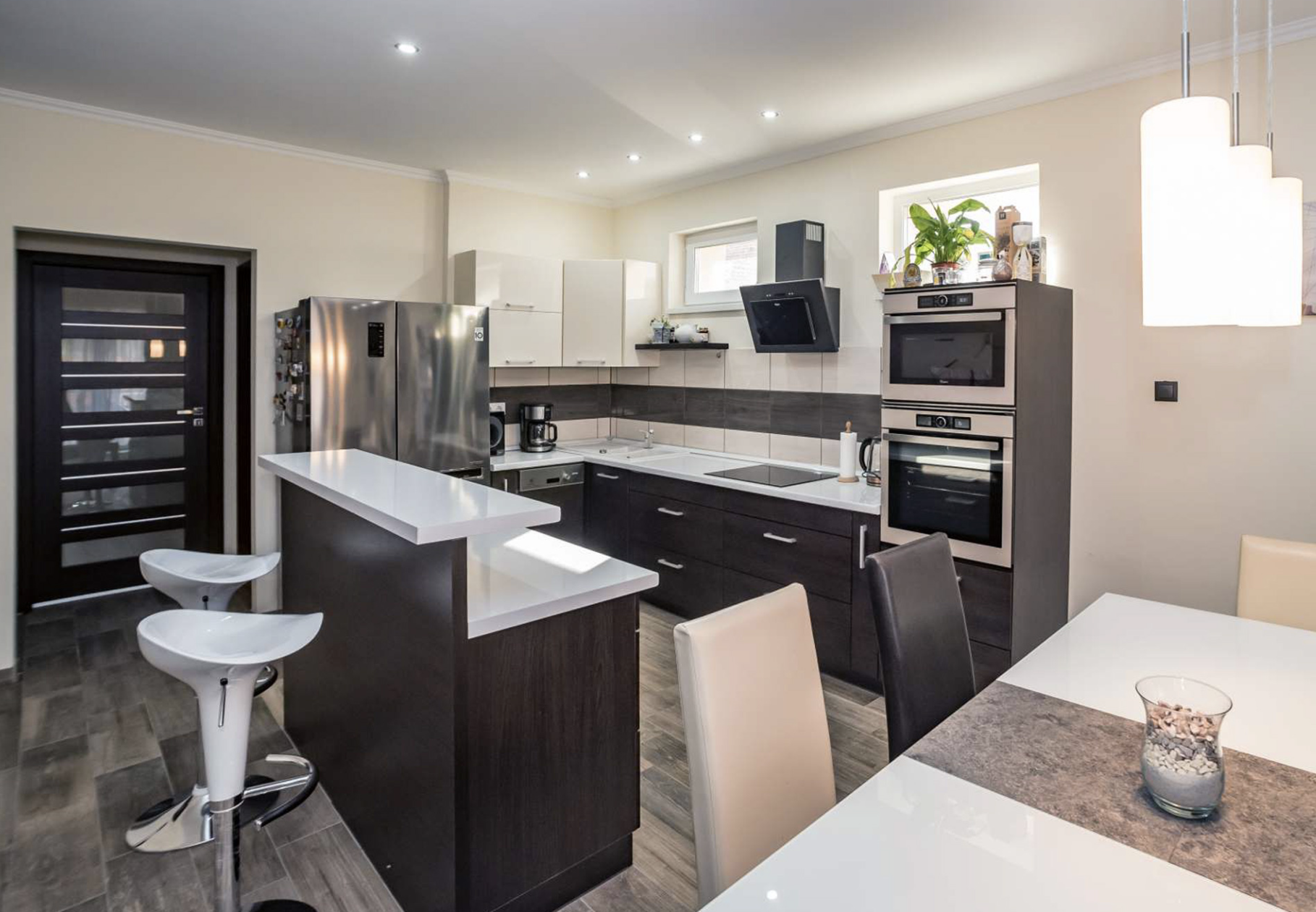 Modern konyha letisztult vonalakkal, fehér és sötétbarna bútorokkal.