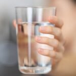 Egy kézben tartott pohár tiszta ivóvíz