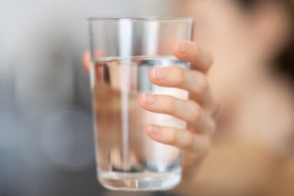 Egy kézben tartott pohár tiszta ivóvíz